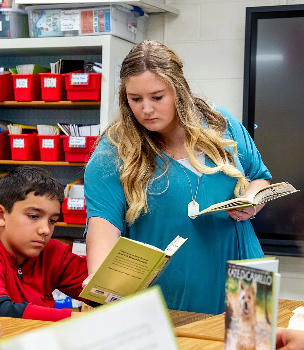 Teacher reading with a student in an elementary classroom.