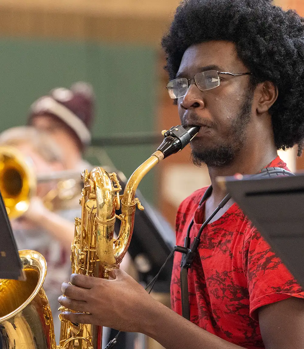 Student playing a saxophone during a rehearsal.