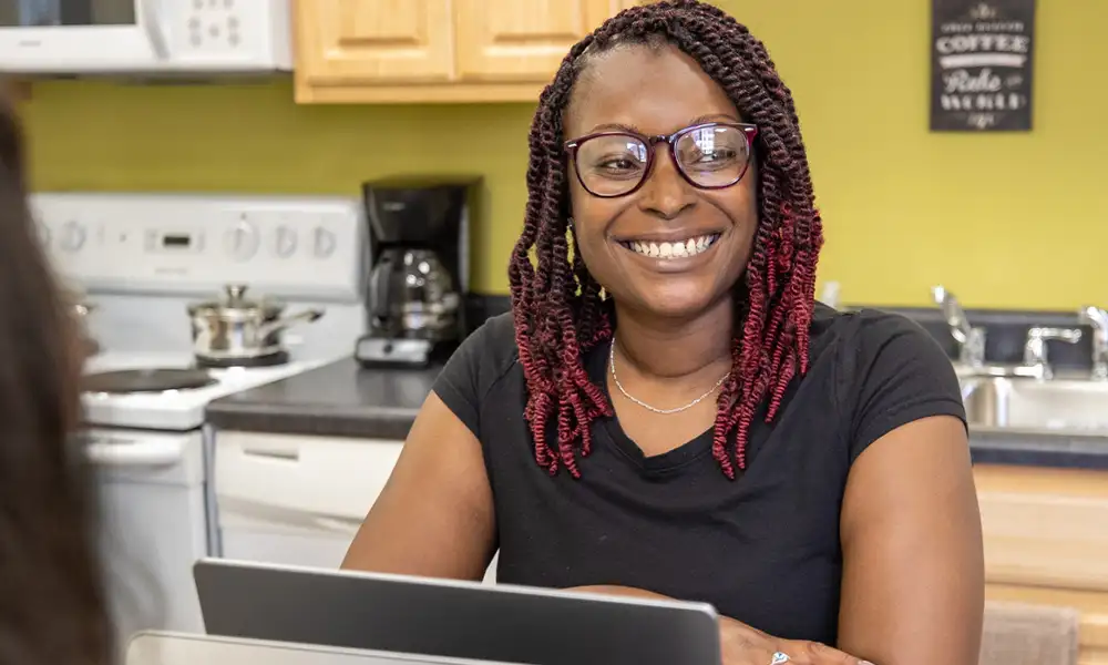 Student using a laptop while seated at a kitchen table.