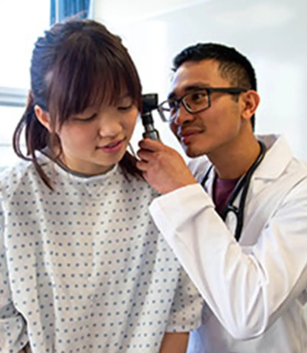 Examining a patient’s ear with an otoscope.