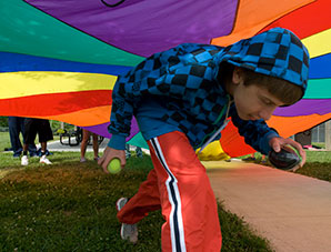Child running under a rainbow parachute during an SIU Special Education camp