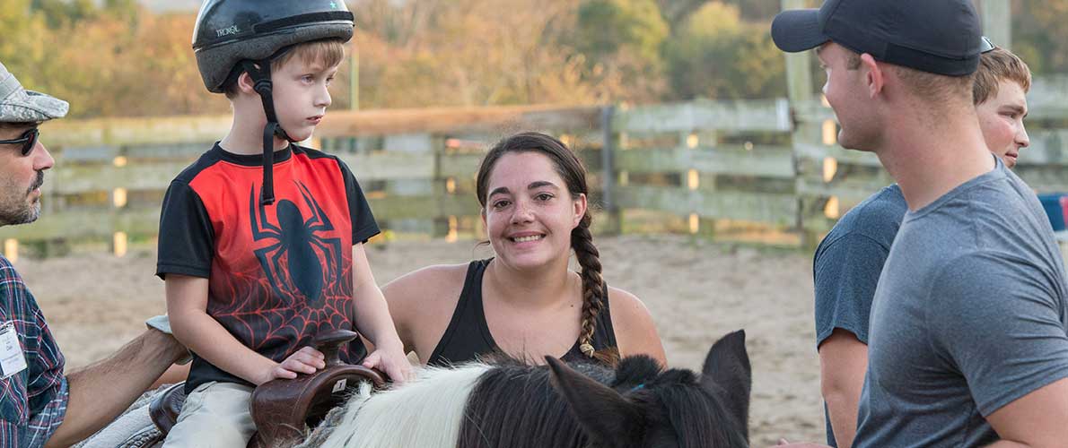 SIU CARE students work with a child on a horse on SIU campus