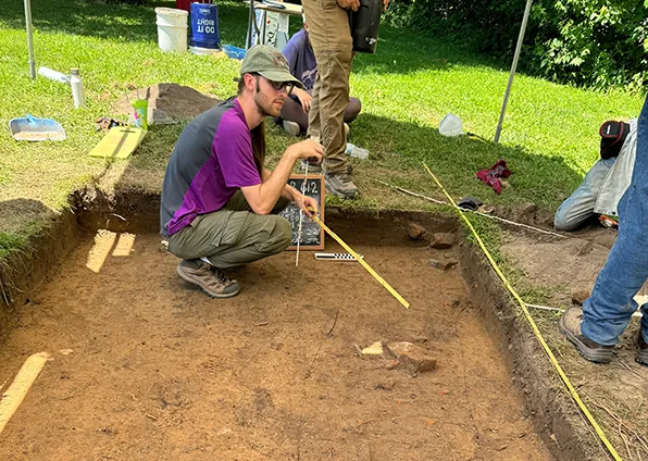 SIU Anthropology Student measuring dig at field camp