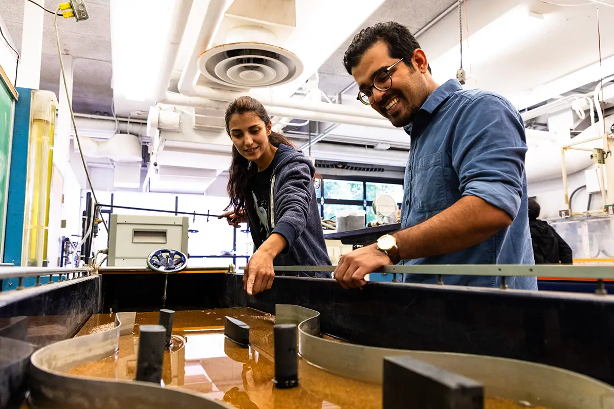 Two students work together at a water flow research apparatus in an engineering laboratory.