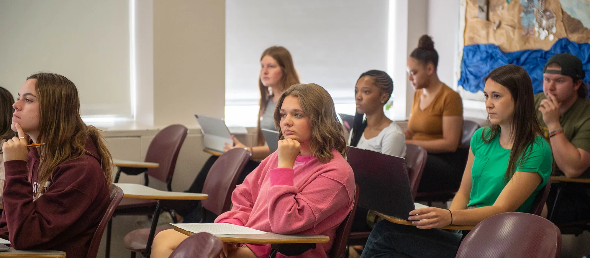 SIU students seated at desks in a college classroom listening to a lecture.
