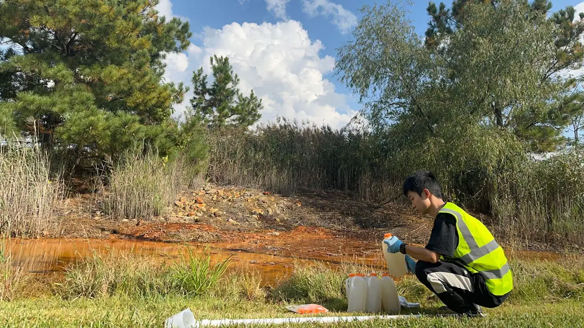 Partha Protim Bhowmik, a graduate student in civil engineering, collects samples from acid run-off at an abandoned coal mine in Southern Illinois.
