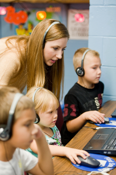 Teacher and student with headphones working on computers